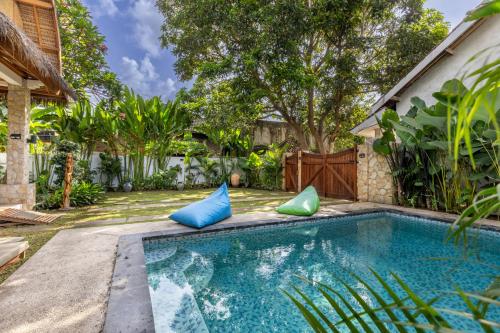 a pool with blue and green pillows next to a house at Villa Trembesi - New Spacious Luxury 2BR Private Villa - Free Gym Access - 60Mbps WiFi in Kuta Lombok