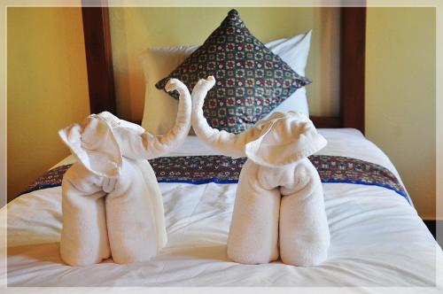two stuffed elephants are standing on a bed at Baan Bussaba Hotel in Trang