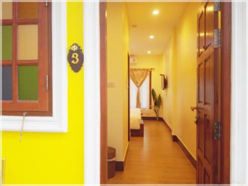 a hallway with yellow walls and a room with a door at Baan Bussaba Hotel in Trang