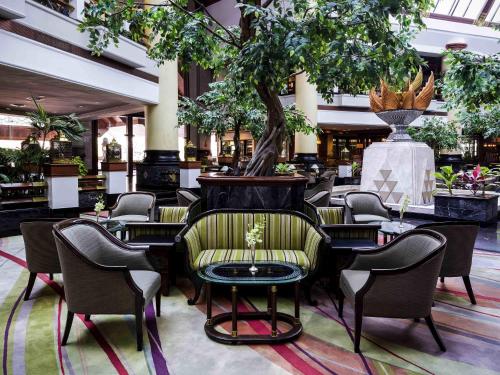 a lobby with chairs and a table and a tree at Pullman Khon Kaen Raja Orchid in Khon Kaen