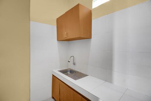 a kitchen with a sink and a wooden cabinet at Hotel O near Trans Studio Theme Park formerly Cyloam Residence in Legian