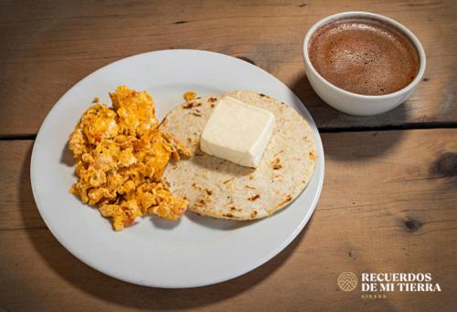 um prato com ovos e queijo e uma xícara de café em Hotel Recuerdos de mi Tierra boutique colonial a pasos de Provenza em Medellín
