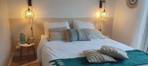 een slaapkamer met een wit bed met kussens en 2 verlichting bij Casa Mahana spa in Saugnacq-et-Muret