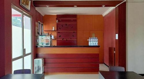 a kitchen with red walls and a counter with chairs at Hotel O Tri Homestay in Palangkaraya