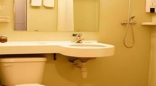 a bathroom with a sink and a toilet and a mirror at Jinjiang Inn Yantai Fushan District Fuhai Road in Yantai