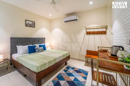 Schlafzimmer mit einem Bett mit blauen Kissen und einem Schreibtisch in der Unterkunft StayVista at The Vara House with AC & Board Games in Varanasi