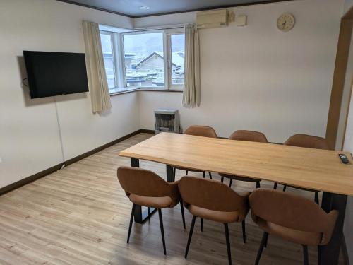 een conferentieruimte met een houten tafel en stoelen bij Frasis in Furano