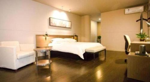 a bedroom with a bed and a chair and a table at Jinjiang Inn select Hotel Kunming Economic Development Zone Kunming College in Kunming