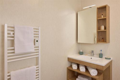 a bathroom with a sink and a mirror and towels at Quality Suites Cholet in Cholet