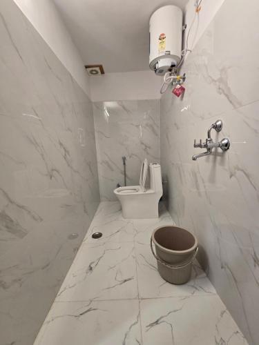 a white bathroom with a toilet and a sink at Kassy homestay in Udaipur