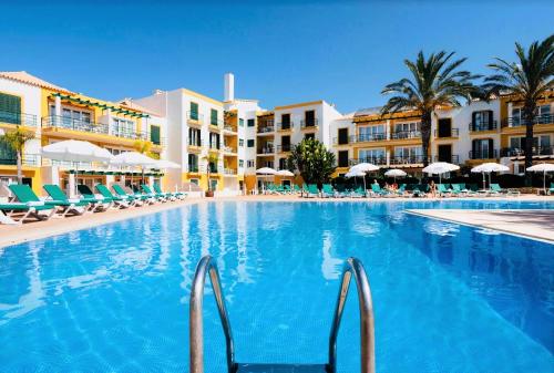 a swimming pool at a resort with chairs and umbrellas at Casa D`Sul by Homing in Tavira