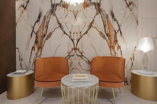 two chairs and a table in a room with a wall at Apeiro City Avant-garde Hotel in Sarajevo