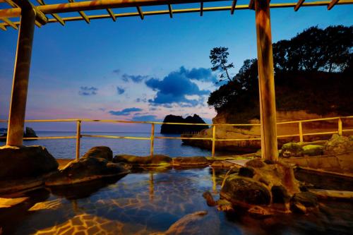 a body of water with rocks and a fence at UmibenokakureyuSEIRYU海辺のかくれ湯清流 in Nishiizu
