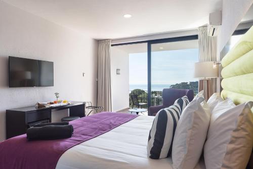 Hotel Eetu Begur, Affiliated by Meliá في بيغور: غرفة نوم بسرير كبير مع نافذة كبيرة