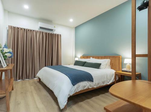 a bedroom with a large bed and a table at Cozy Nest Ladprao - 3BR Townhome 3min walk from MRT in Bangkok