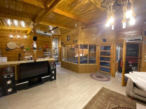 كوخ الوهط الريفي في الطائف: غرفة معيشة كبيرة بجدران خشبية وجهاز تلفزيون كبير