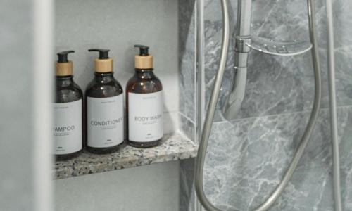 a group of four bottles on a shelf in a bathroom at Cozy Nest Ladprao - 3BR Townhome 3min walk from MRT in Bangkok