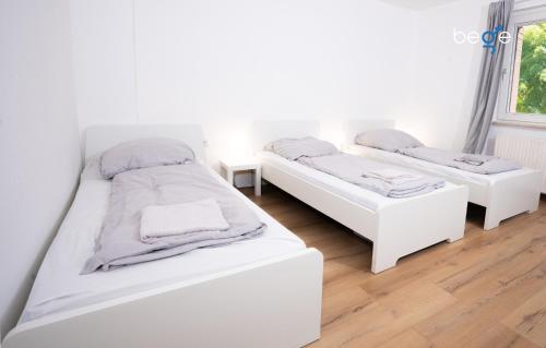 two white beds in a room with a window at BEGE APARTMENTS LightHaus in Holzwickede