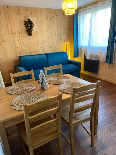 une table à manger avec des chaises et un canapé bleu dans l'établissement Studio cosy au pied de la télécabine pour l Alpe d Huez Parking privé, à Allemont
