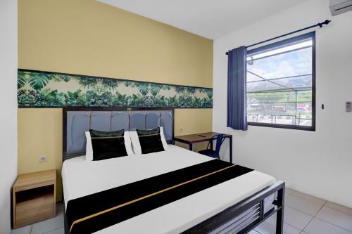 a bedroom with a large white bed with a window at Hotel O near Trans Studio Theme Park formerly Sunset Cozy Residence in Mantaak