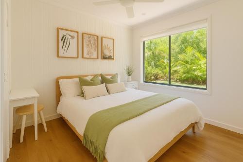 a white bedroom with a large bed and a window at LUXE Tropical oasis, magnesium pool, 4bed in Noosa Heads
