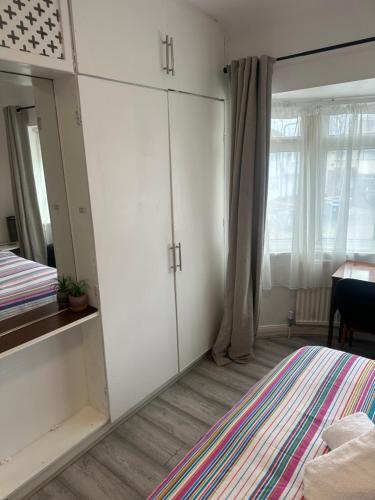 a bedroom with a large white cabinet and a bed at Standard Double Room near OVO Wembley Stadium in London