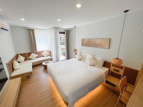 Un dormitorio con una gran cama blanca y un sofá. en Wyndham Garden Samui Wing, en Koh Samui 