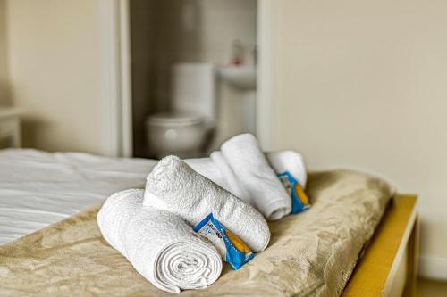 a pile of towels sitting on top of a bed at Spacious 4 Bedroom Warrington House with Free Parking Perfect for Contractors, Families and Business Guests in Great Sankey