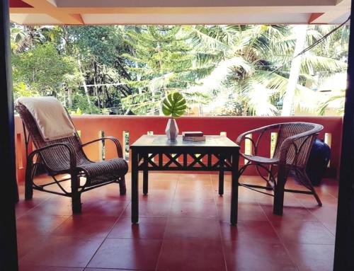 a patio with two chairs and a table with a plant on it at NeelaHouse in Kovalam