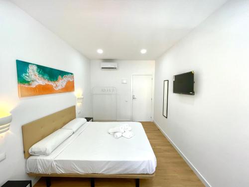 a white room with a bed and a tv at Lux Hostal in Hospitalet de Llobregat