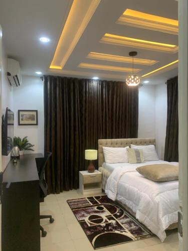 a bedroom with a bed and a desk and curtains at Ozin Retreat And Wellness Home in Ikeja