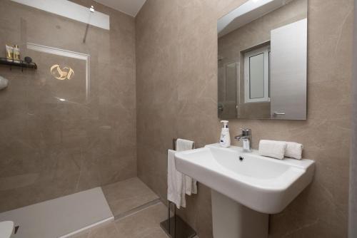 a bathroom with a sink and a mirror and a shower at Elmswater court in St. Paul's Bay