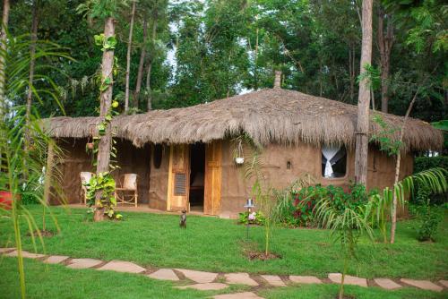 a small hut with a grass roof in a forest at Mtoni River Lodge in Arusha