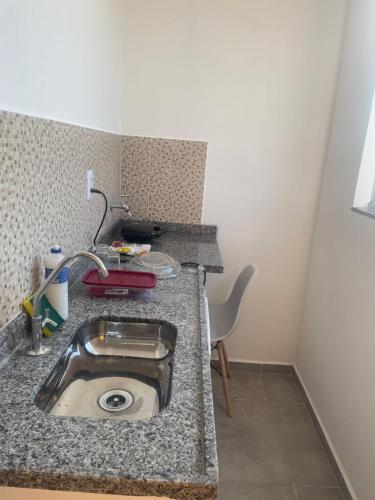 a kitchen counter with a sink and a chair at Flat 2 ao lado da UFSJ e Igreja São Francisco in São João del Rei