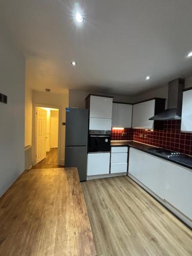 een keuken met witte en zwarte apparatuur en houten vloeren bij Big Double room wimbledon Park in Londen