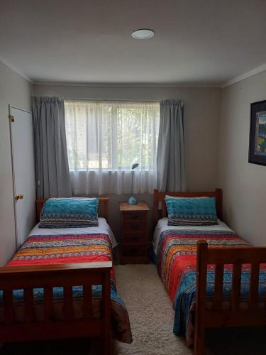 a bedroom with two beds and a window at Driftwood Sands 3 Brm in Tairua