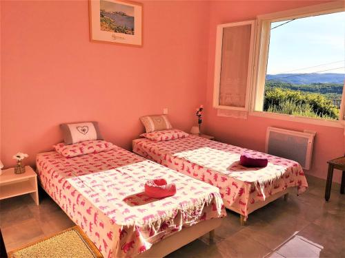 two beds in a room with pink walls and a window at L'Olivade Large villa with heated swimming pool in Entrecasteaux