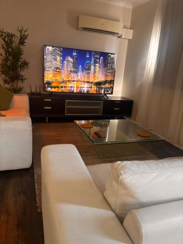 a living room with a tv and a white couch at East Perth 2 bedroom Apartment with Parking and Wi-Fi in Perth
