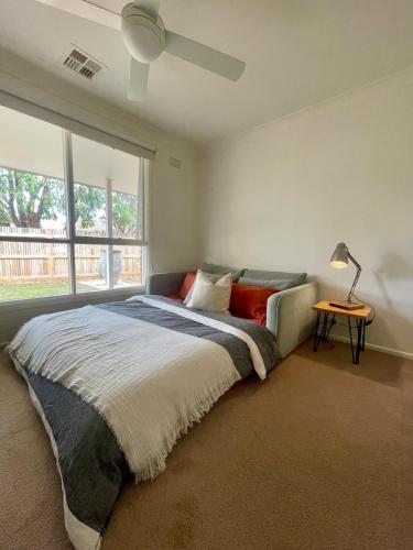 a bedroom with a bed with a lamp and a window at Lonny Coastal Escape in Point Lonsdale