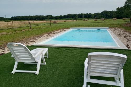 2 sillas sentadas junto a una piscina en La Grande Métairie Notz Marafin, en Paulnay