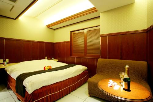 a bedroom with a bed and a table with a bottle of wine at ホテル グリーンヒルAdult only in Tokyo