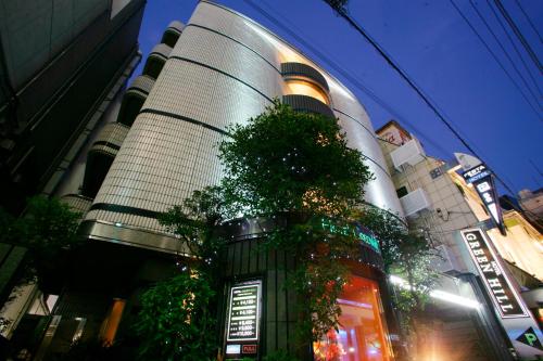 a tall building with a tree in front of it at ホテル グリーンヒルAdult only in Tokyo