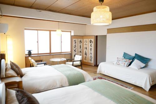 ein Hotelzimmer mit zwei Betten und einem Tisch in der Unterkunft 宇都宮ゲストハウス花ニ嵐 in Utsunomiya