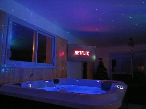 een badkuip in een kamer met een bordje waarop 'Netflix' staat bij Logement insolite avec Jeux et Jacuzzi in Soulosse-sous-Saint-Élophe
