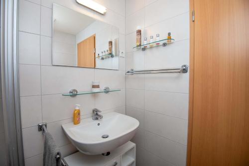 a white bathroom with a sink and a mirror at Ferienwohnung Krabbe in Manslagt