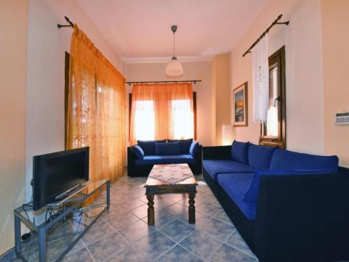 uma sala de estar com um sofá azul e uma TV em Casa Plagia by RentalsPro - Nea Plagia Halkidiki em Nea Plagia