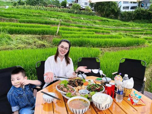een vrouw en een kind aan een tafel met eten bij MT House With Mountain View - Sa Pa Trekking Tour in Sa Pa
