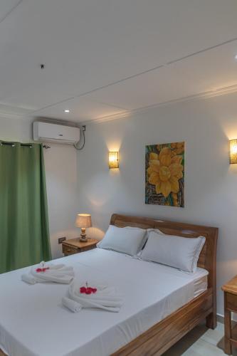 a bedroom with a white bed with two napkins on it at Yvon's Tropical Villa in Grand Anse