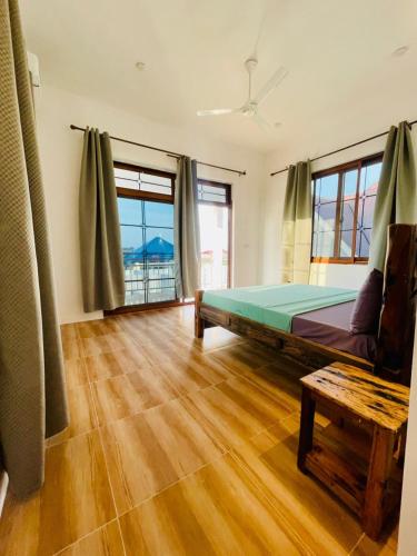 a bedroom with a bed and a table and windows at Leo Home in Nungwi