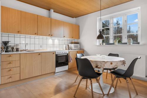 a kitchen with wooden cabinets and a table and chairs at Naturskønt nær Ribe Vikingecenter, se og oplev den gamle by Ribe in Ribe